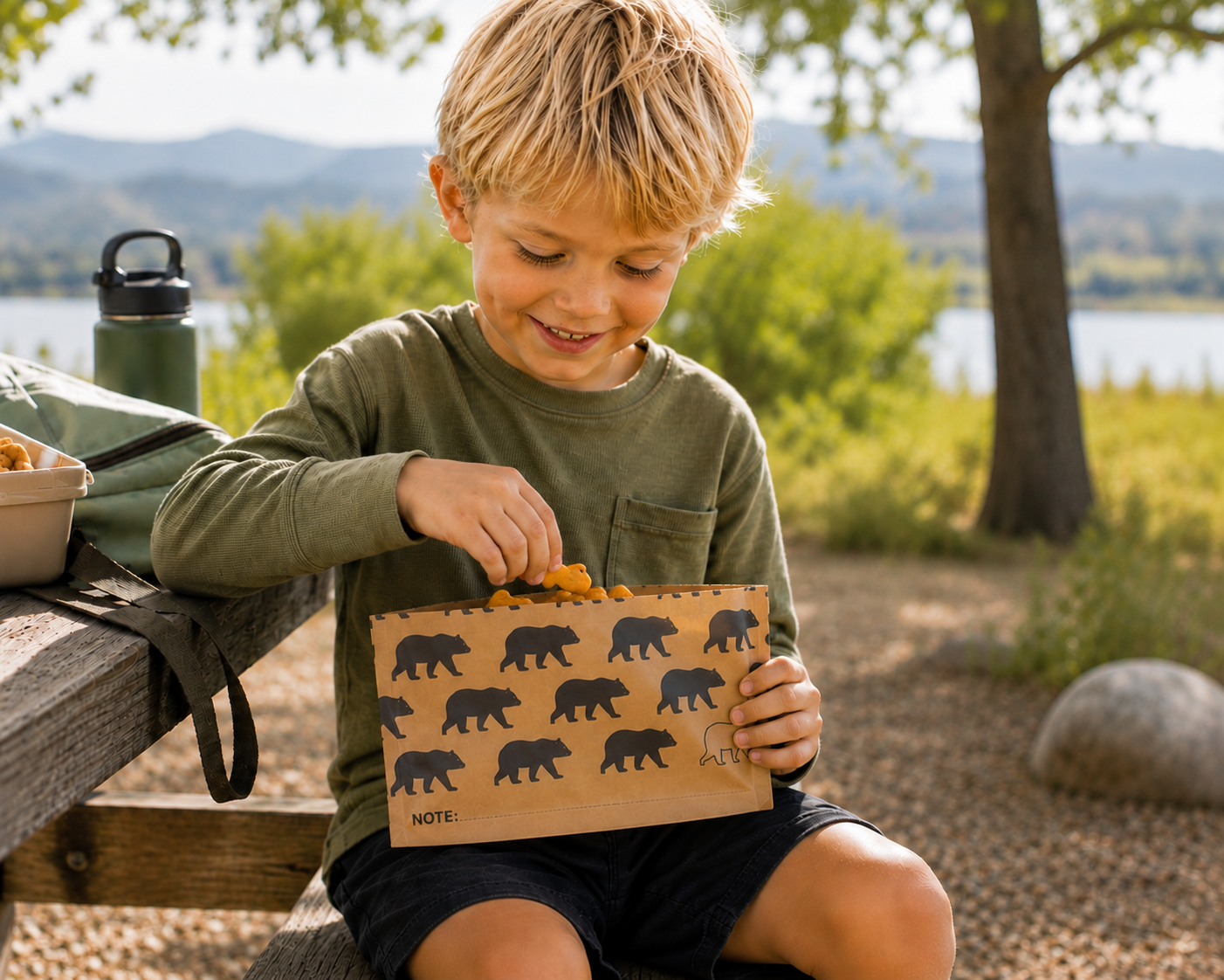 Image of Child holding a bag with bear designs outdoors near a lake