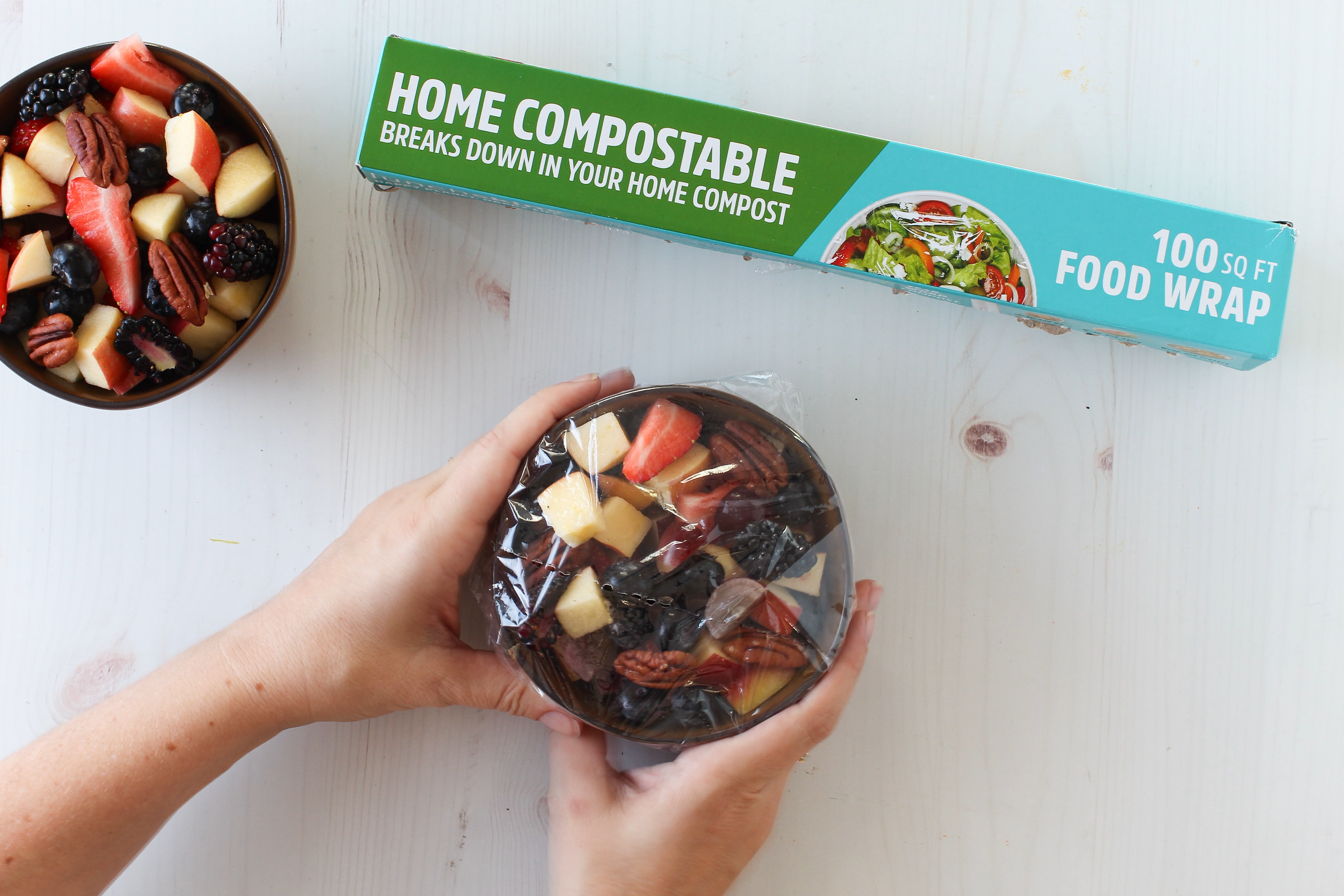 Home compostable food wrap packaging with a person holding a wrapped fruit salad.